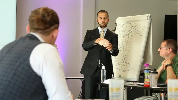 Birol Isik erklärt an einem Flipchart mit Gehirn-Skizze, wie Denkmuster entstehen und sich verändern lassen